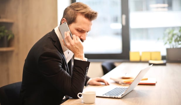 man-having-a-phone-call-in-front-of-a-laptop-859264